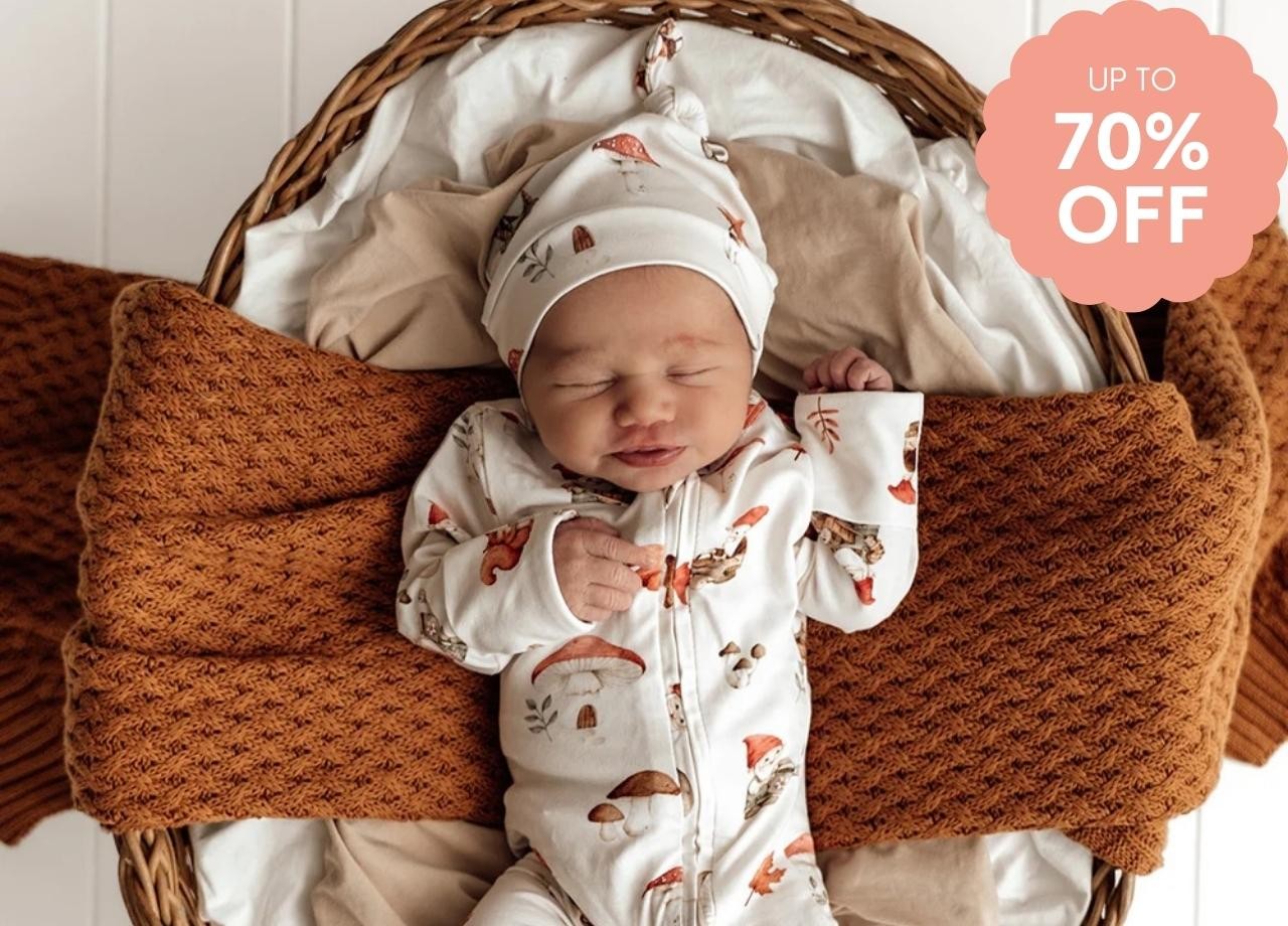 A baby in a snuggle hunny romper sleeping in a basket