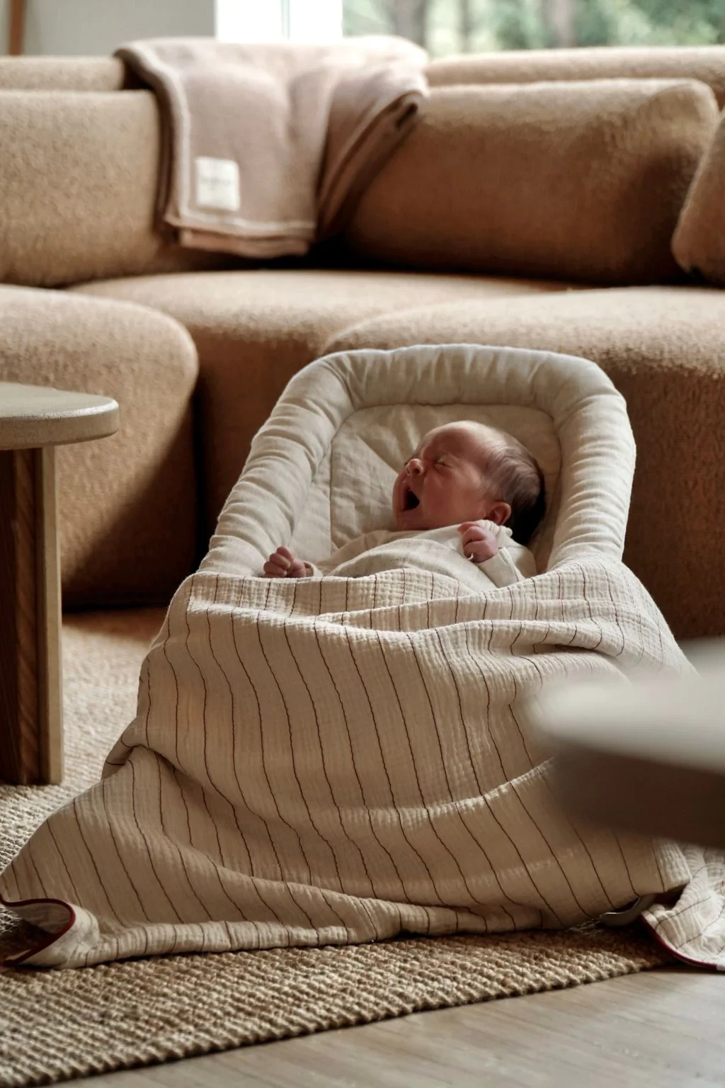 The sacred bundle baby bouncer with a newborn in it, a blanket over their legs