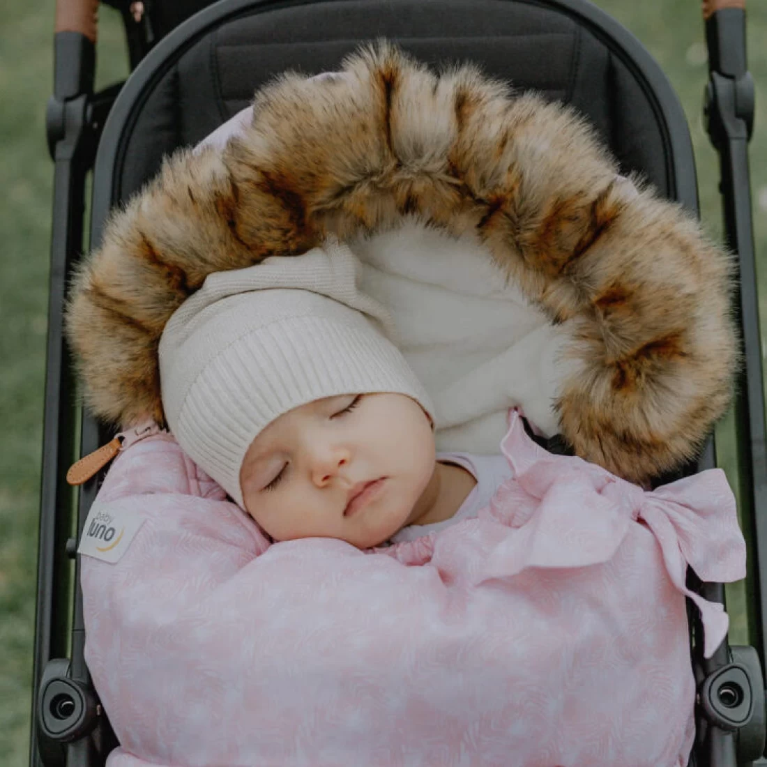 Pram with sleeping baby wrapped in blanket showing best pram liner fitted.