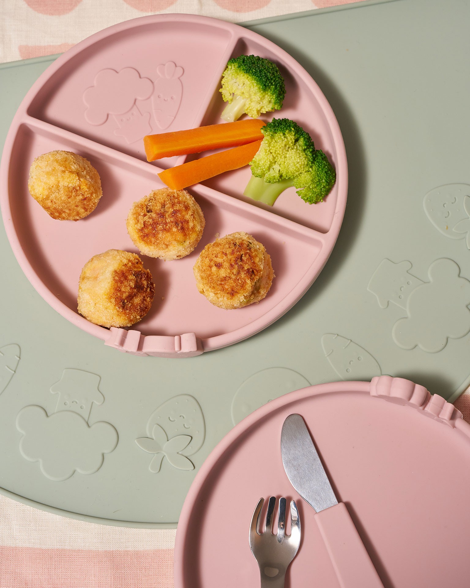 Carrots, broccoli and salmon balls served on a pink Annabel Karmel baby plate as finger food for babies during early solids.