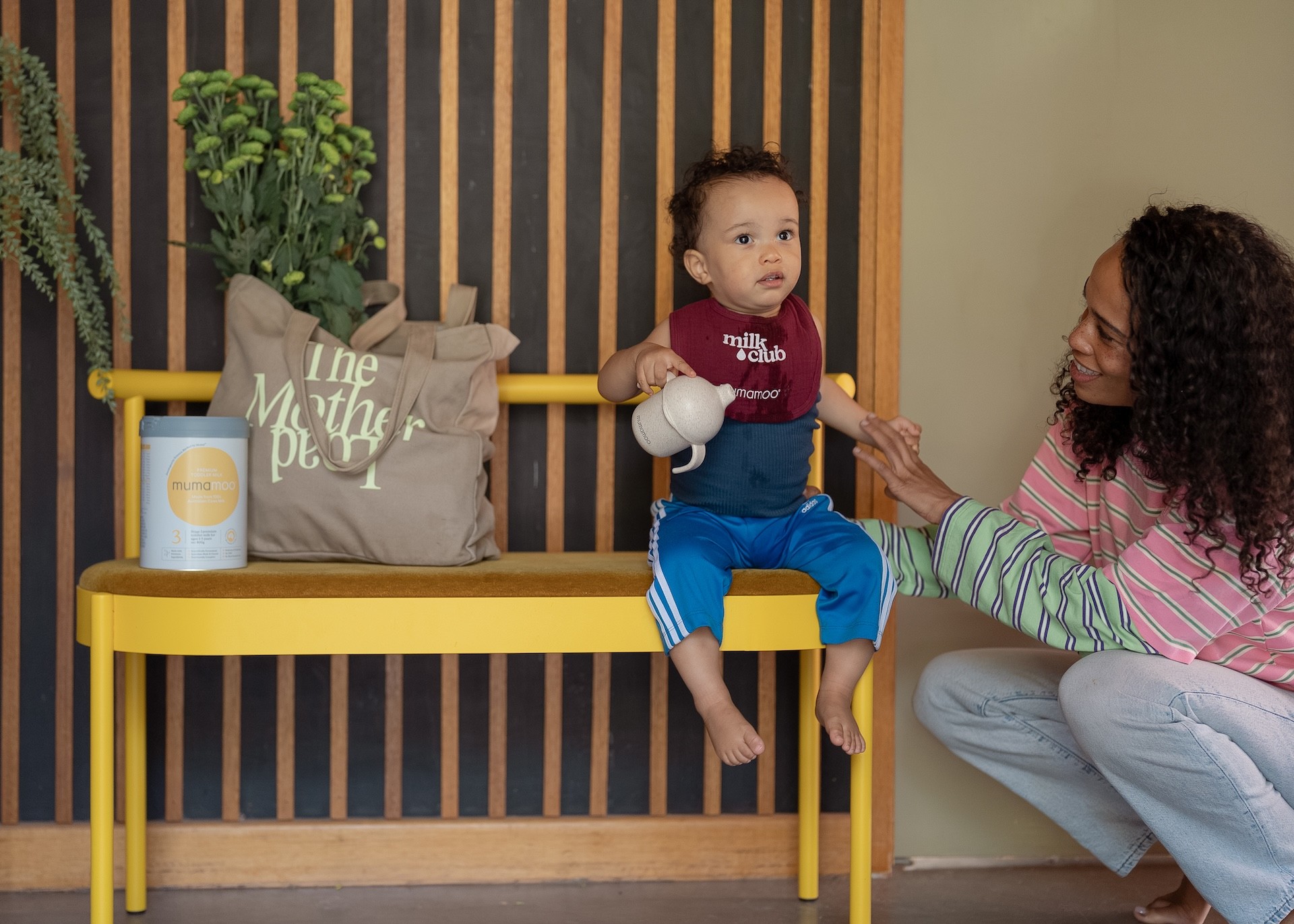 A toddler sitting with his mother and a tin of Mumamoo toddler milk in Australia