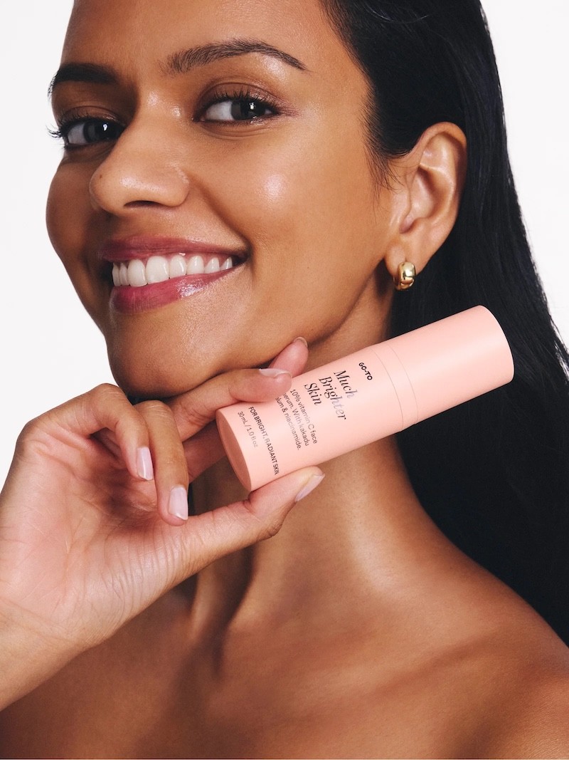 A woman smiling at the camera holding pregnancy safe skincare brand, go-to