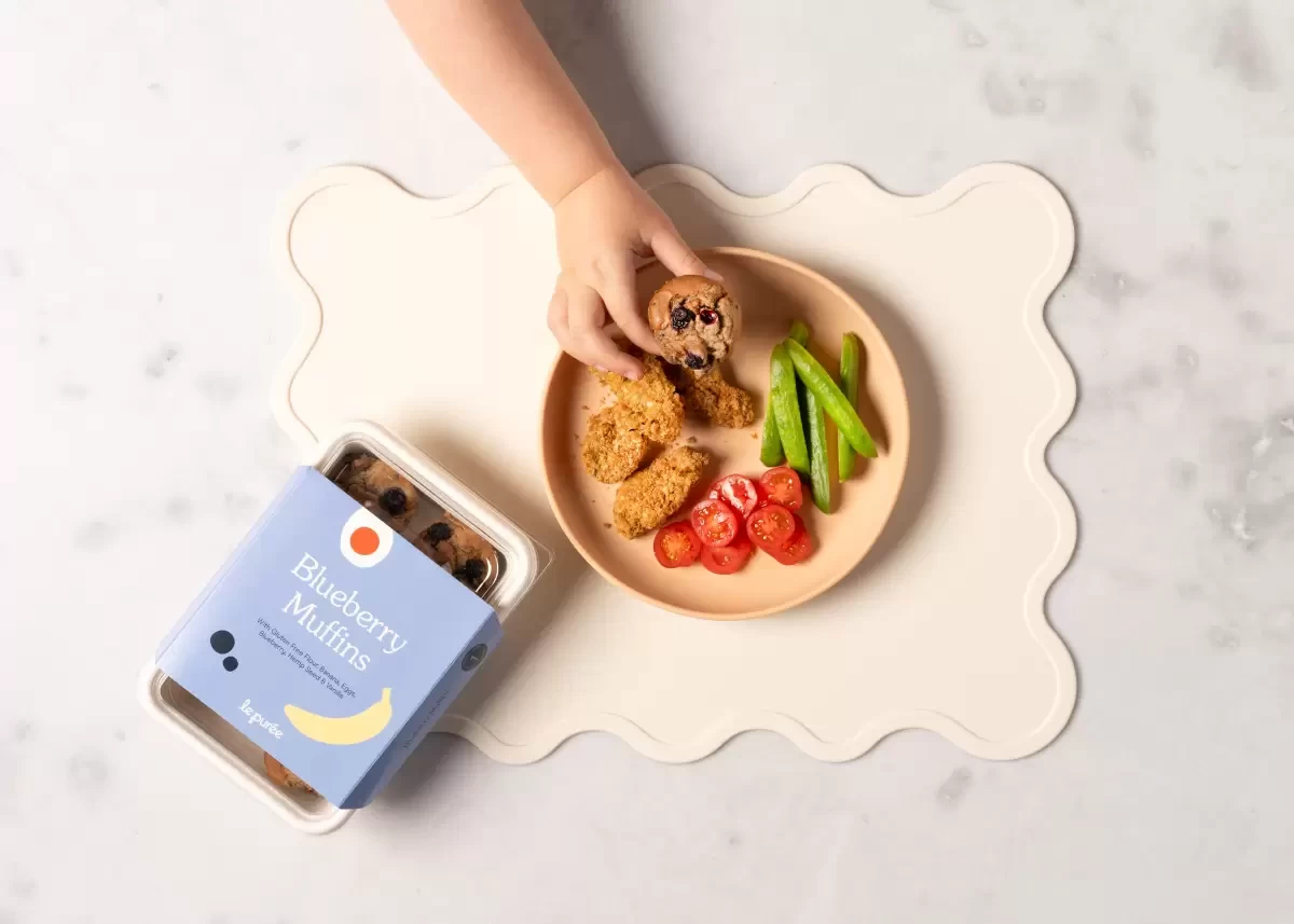 A toddler taking food from a silicone baby plate