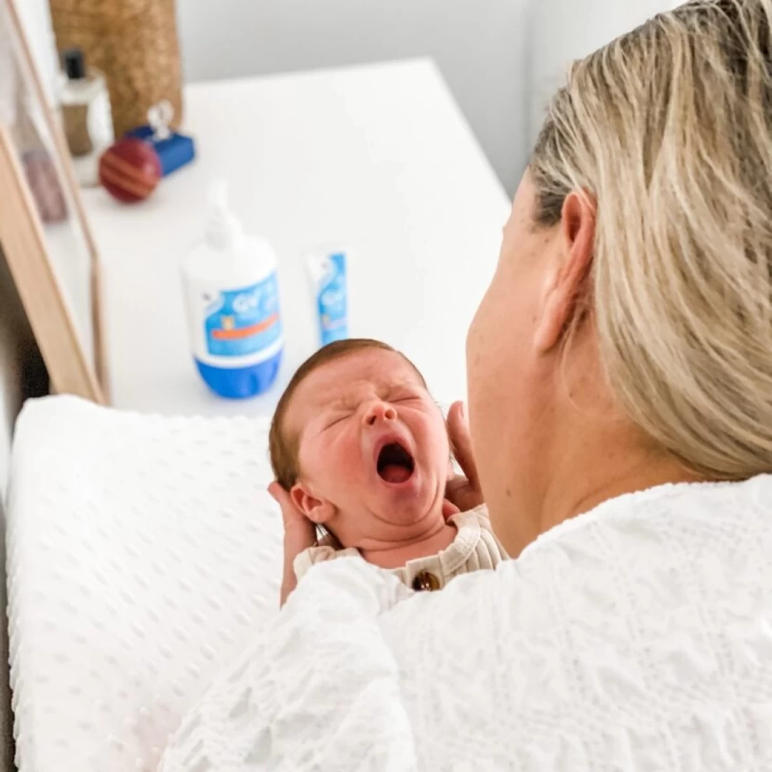 Baby yawning while being bathed, showing comfort from the best newborn essential.