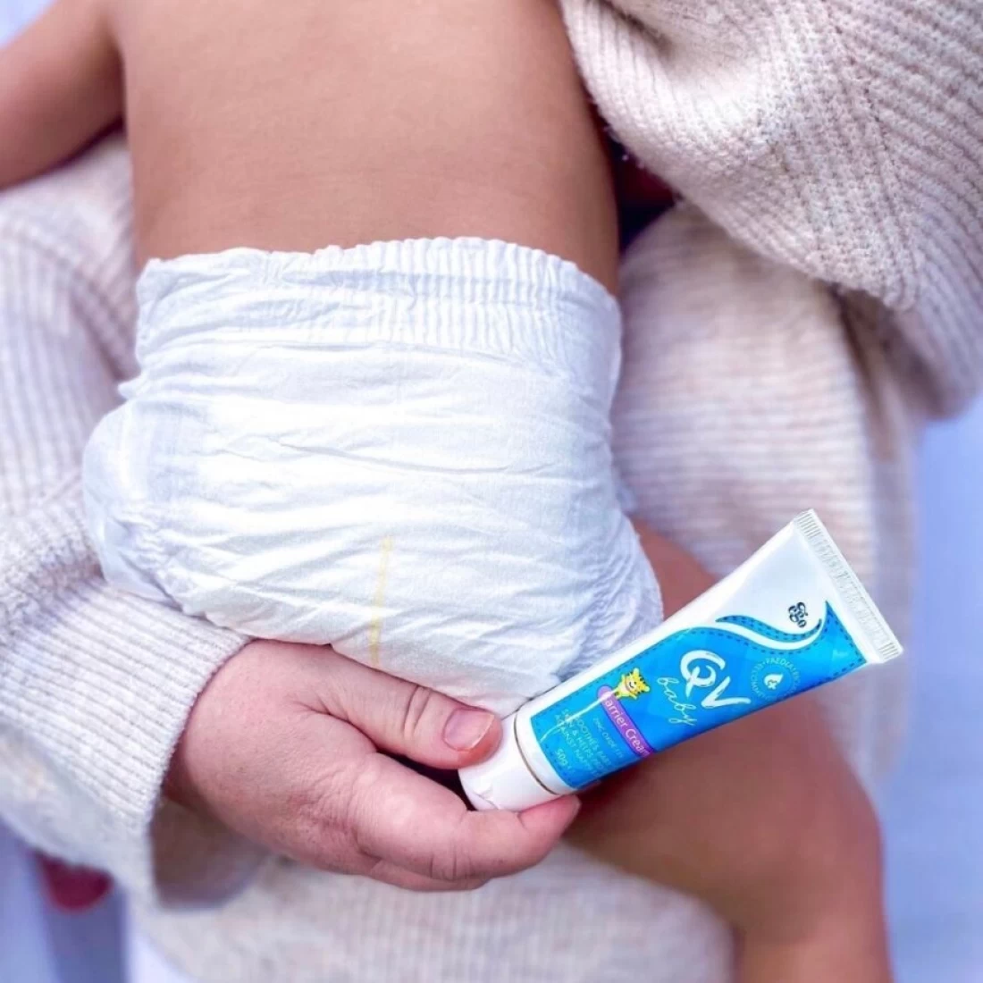 Close-up of baby cream tube in hand, part of the best newborn essential kit.
