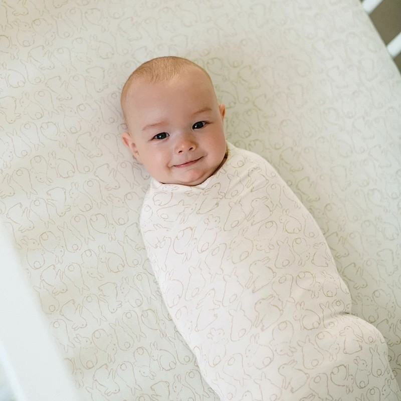 A baby in a swaddle smiling at the camera