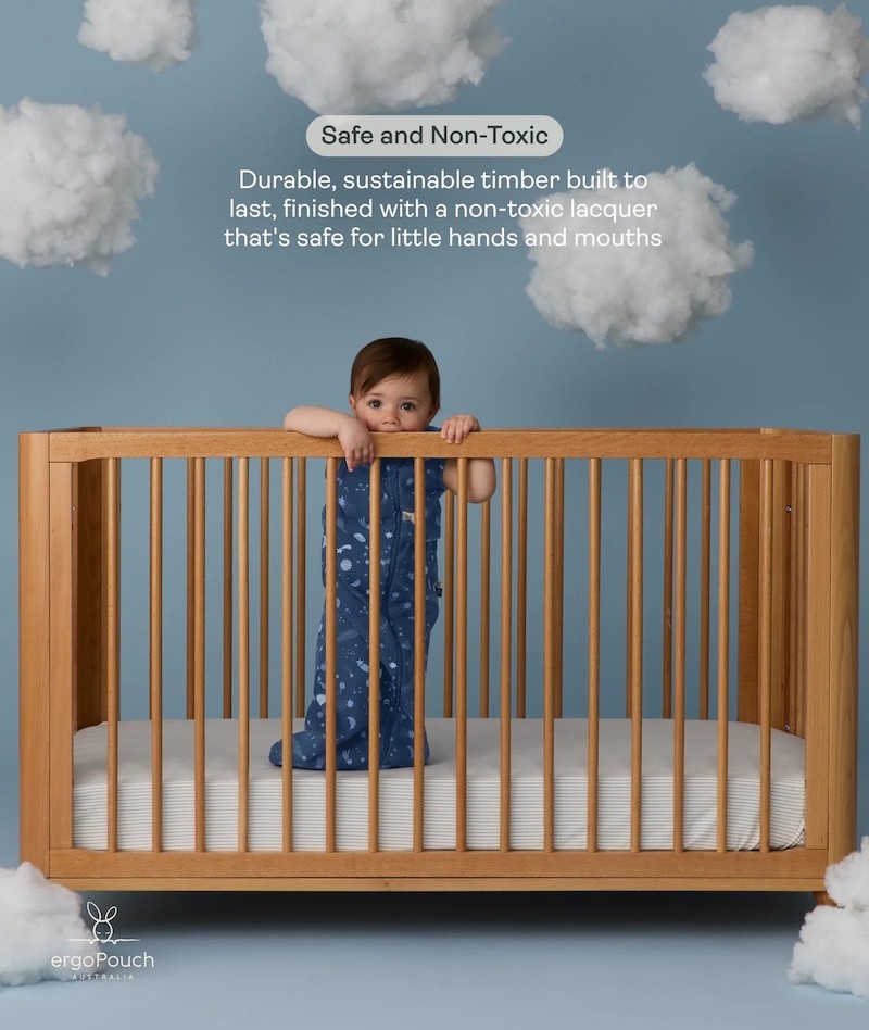 A baby chewing on the side of the Lyra cot