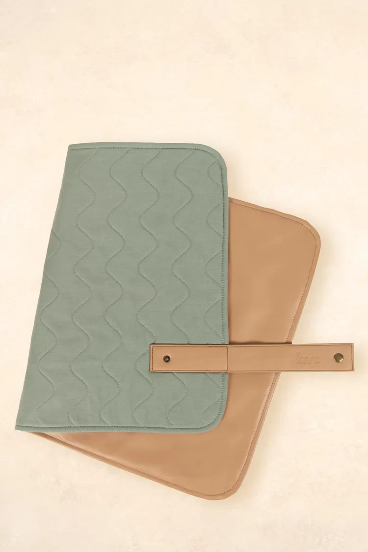 The Kiin travel change mat folded in half, showing the sage front and tan coloured back