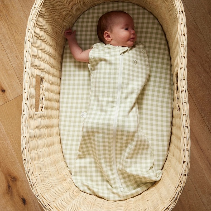 A baby in a sustainable eco friendly swaddle and bassinet sheet by Grow Kindly
