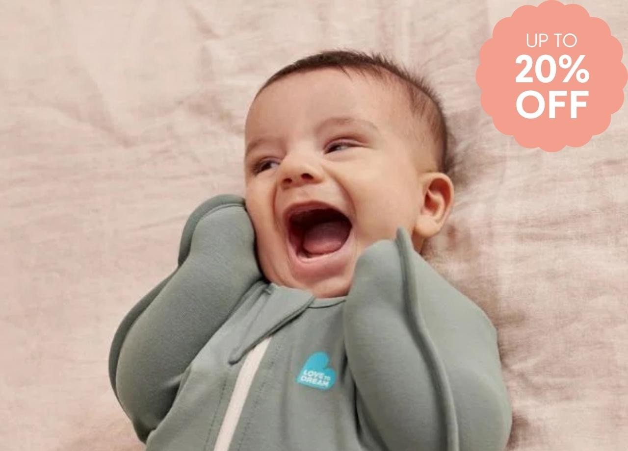 a baby in a love to dream swaddle laughing