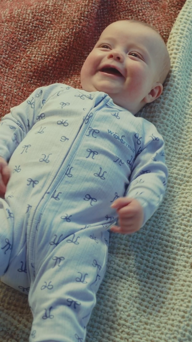A baby smiling wearing a bonds zip growsuit