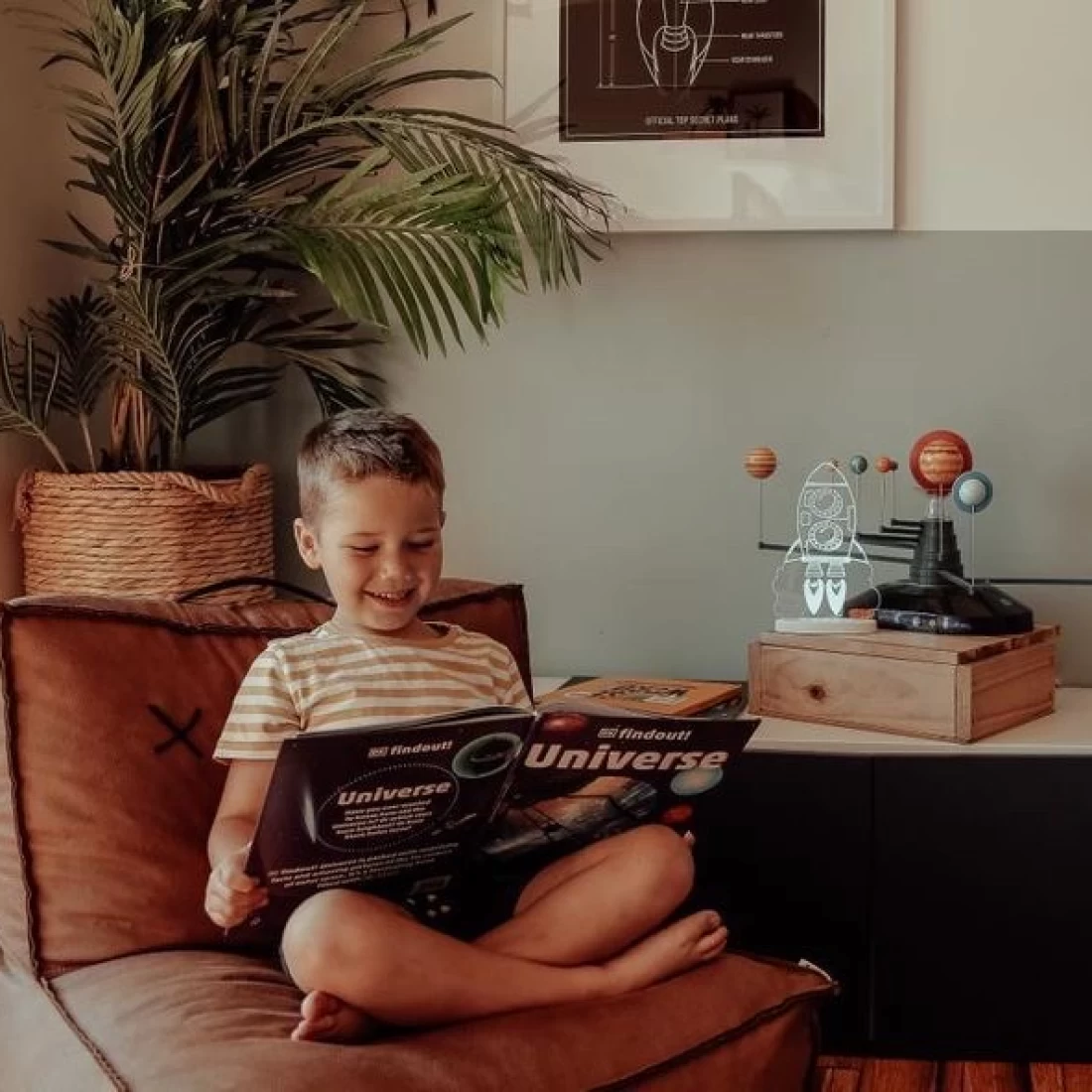 Toddler on chair reading a book with best night light on the nearby table