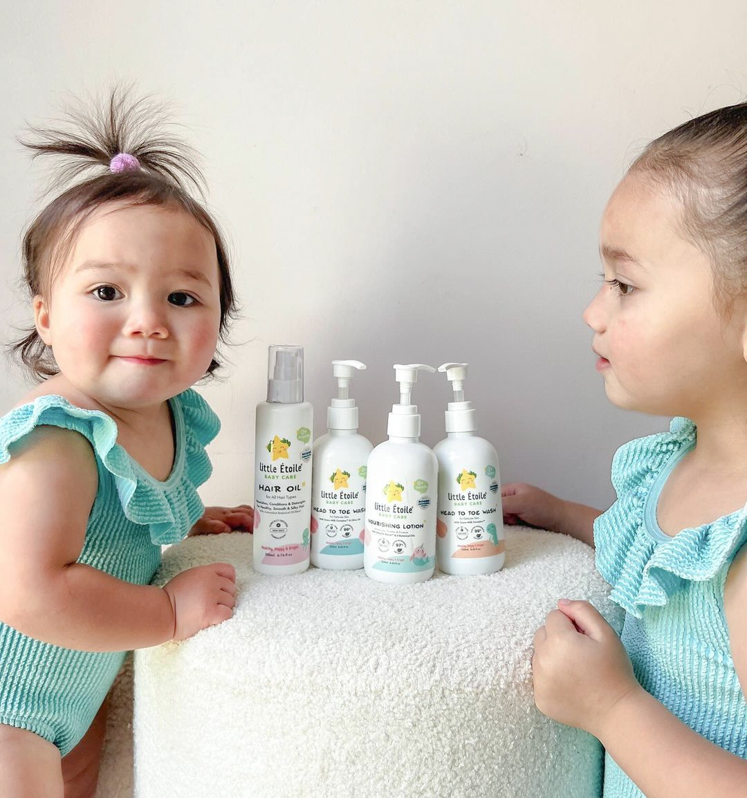 Two toddlers with Little Étoile Baby Care products on the table in front of them