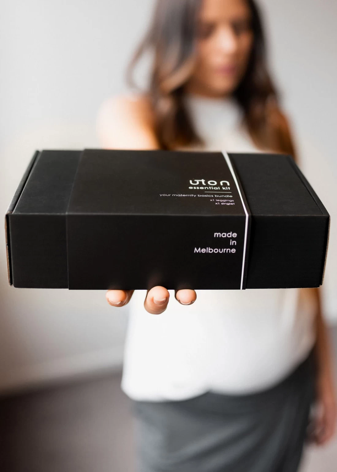 Pregnant mum holding a black Úton box, showcasing premium maternity wear packaging.