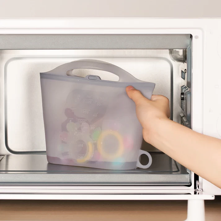 The Haakaa steam steriliser bag with baby toys in it, being put in a microwave