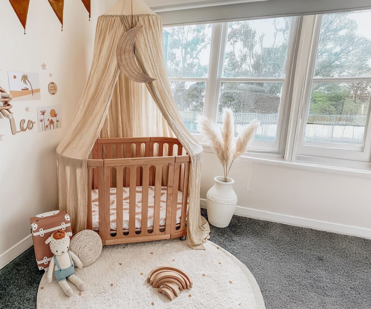 The babyhood kalulya suva cot with hanging curtains over it, in a baby room