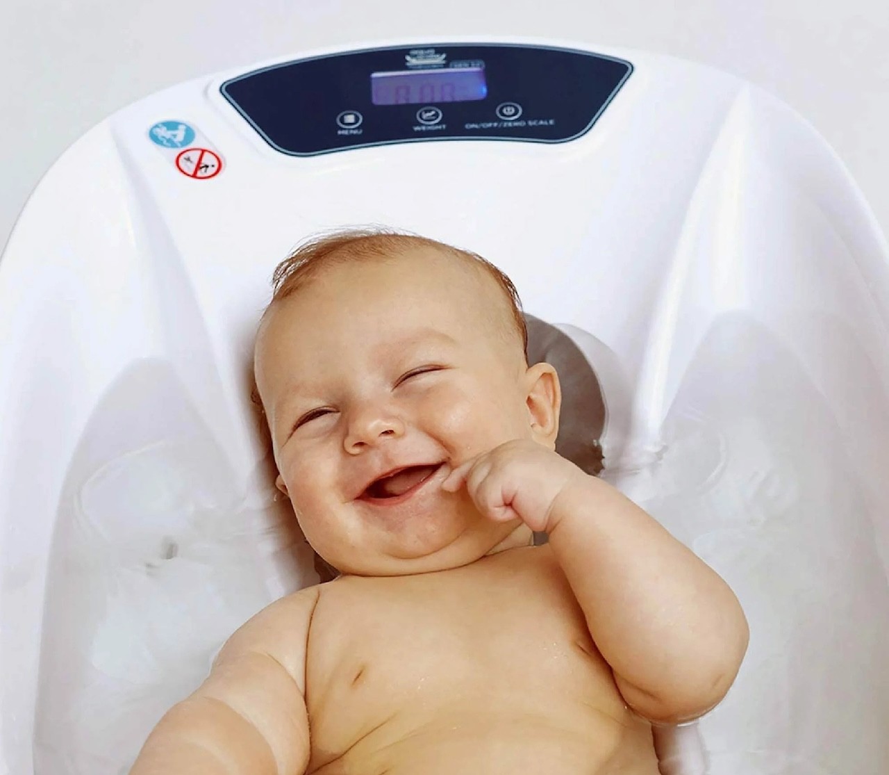 A baby smiling in a baby bath, a newborn essential