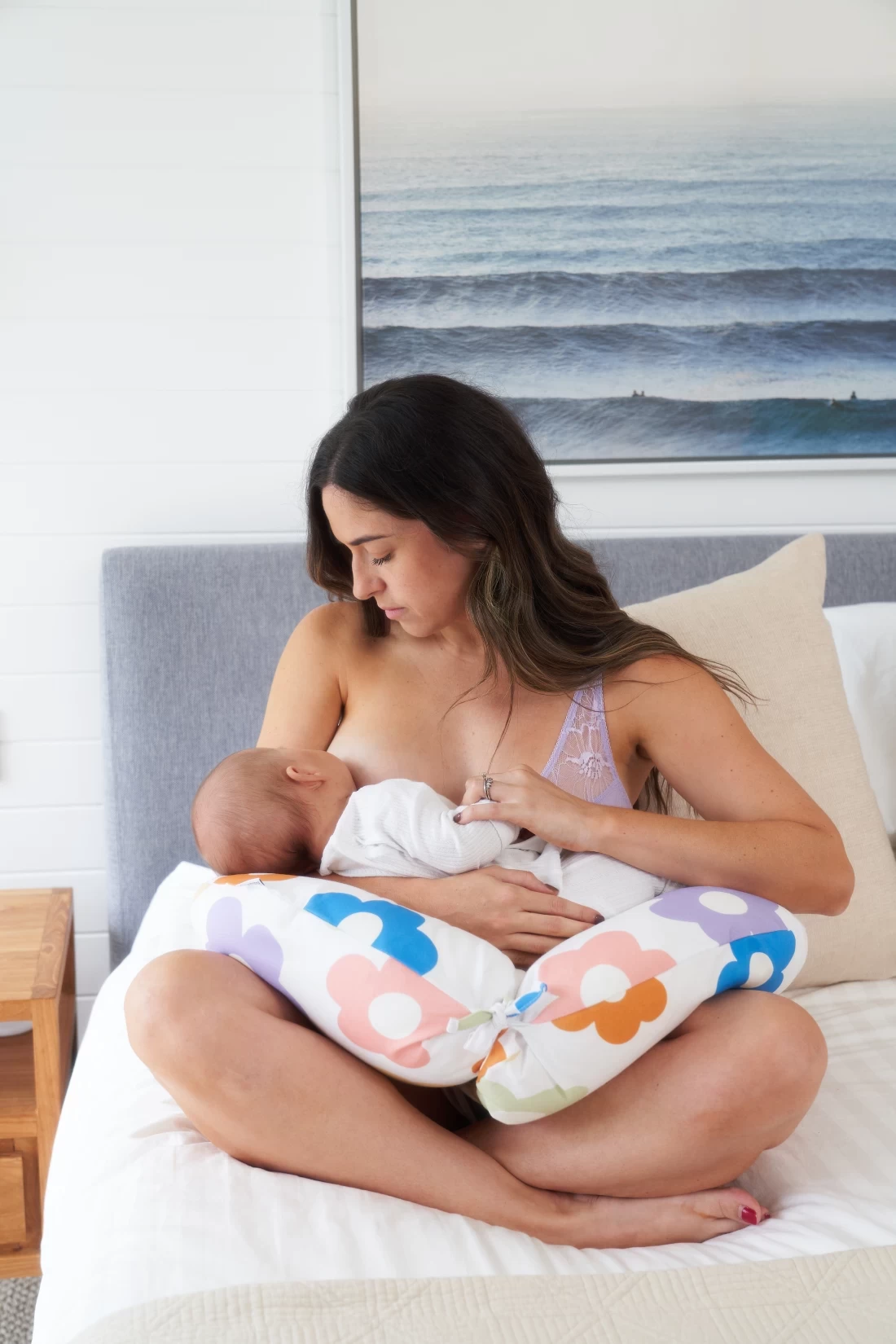 A mum using her butterfly pregnancy pillow to assist holding her newborn baby while feeding