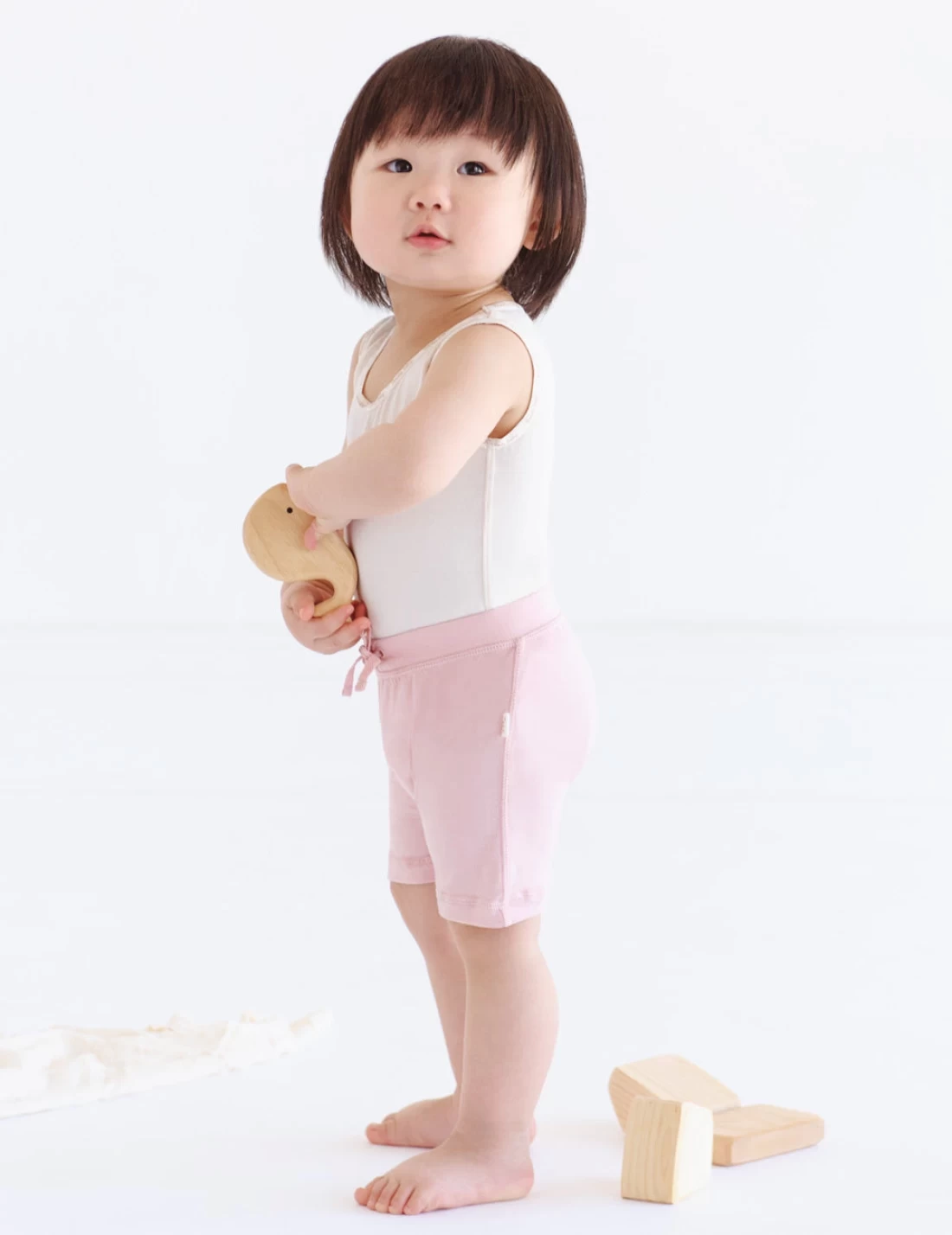 Baby girl standing on white background wearing Boody Bamboo Baby Clothing, showcasing the best baby clothes for softness and eco-friendliness