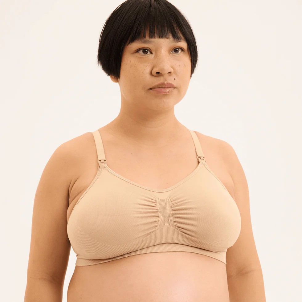 Pregnant woman modelling a nude breastfeeding nursing bra with soft fabric and supportive fit.
