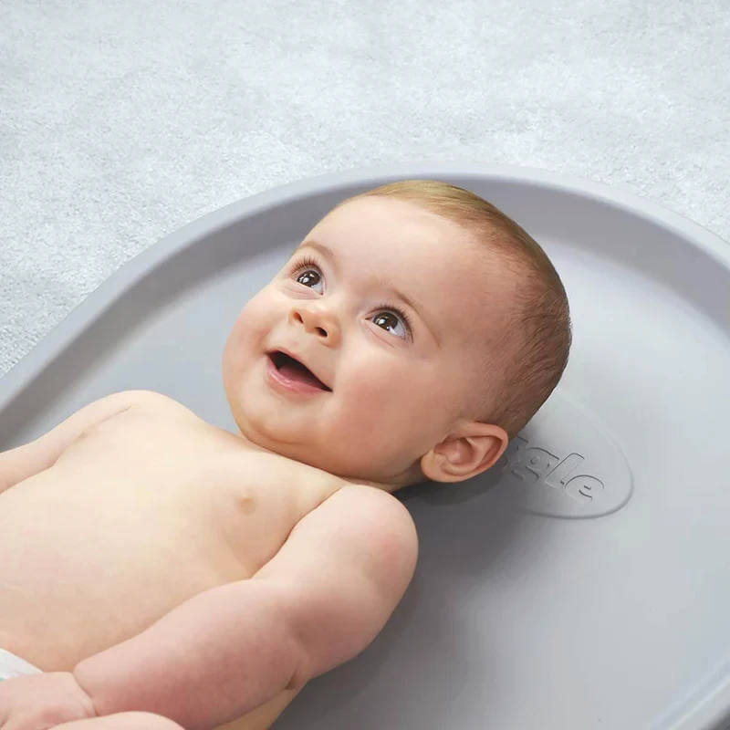 A baby lying on a Shnuggle changing mat in a nursery