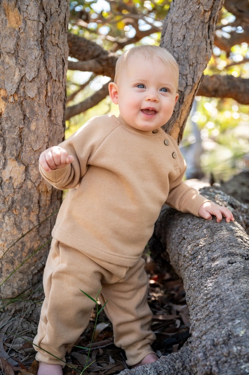 A baby in organic baby clothing in a beige colour