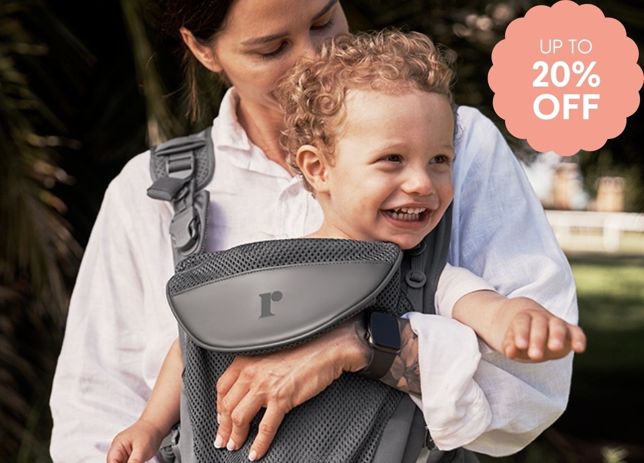 A baby laughing in a baby carrier