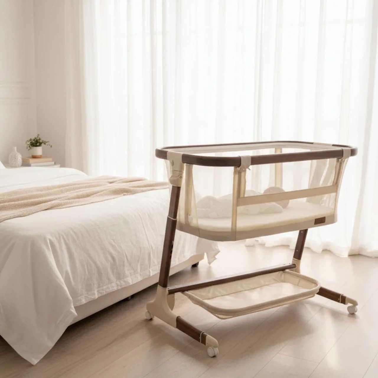 The babystudio baby bassinet at the end of a queen sized bed in a bedroom