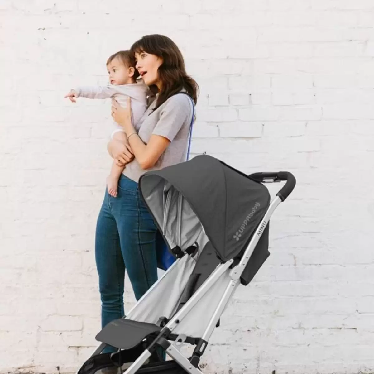 Mum carrying her baby beside the UPPAbaby MINU – the best travel stroller for Australian families