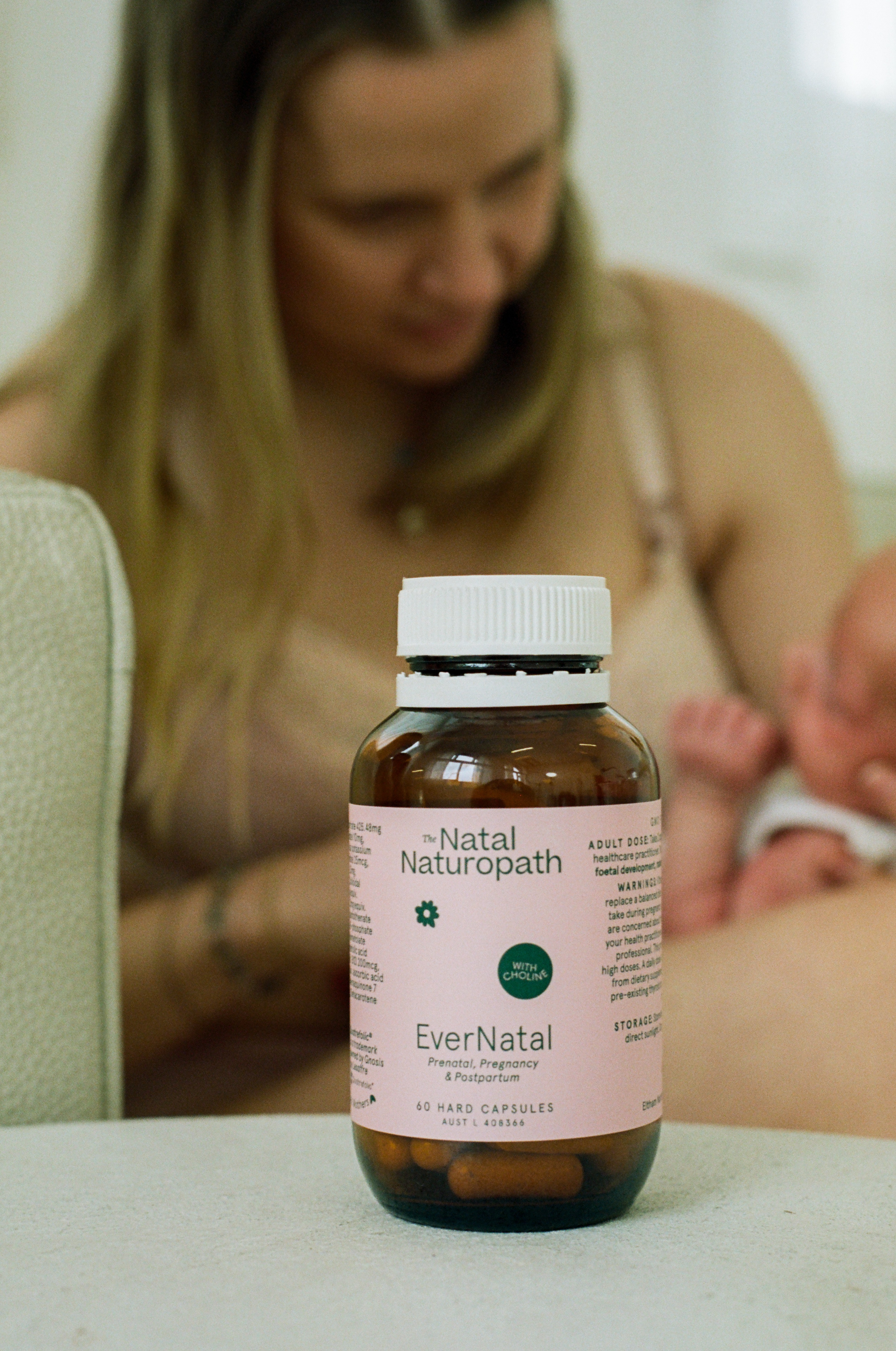 Expecting mum holding Ironbiotic By The Natal Naturopath prenatal vitamin bottle with baby