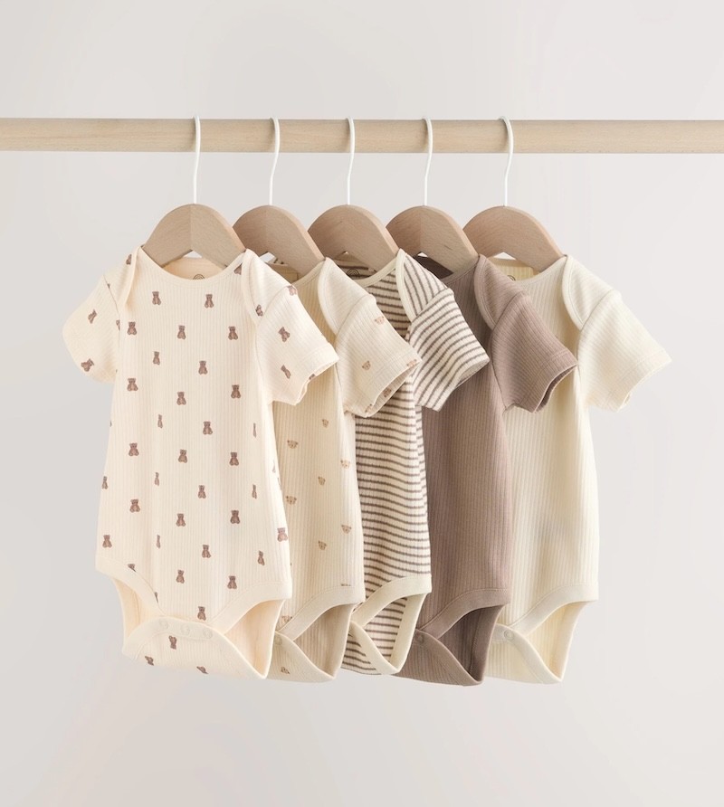 the next australia baby bodysuits hanging on a clothing rail