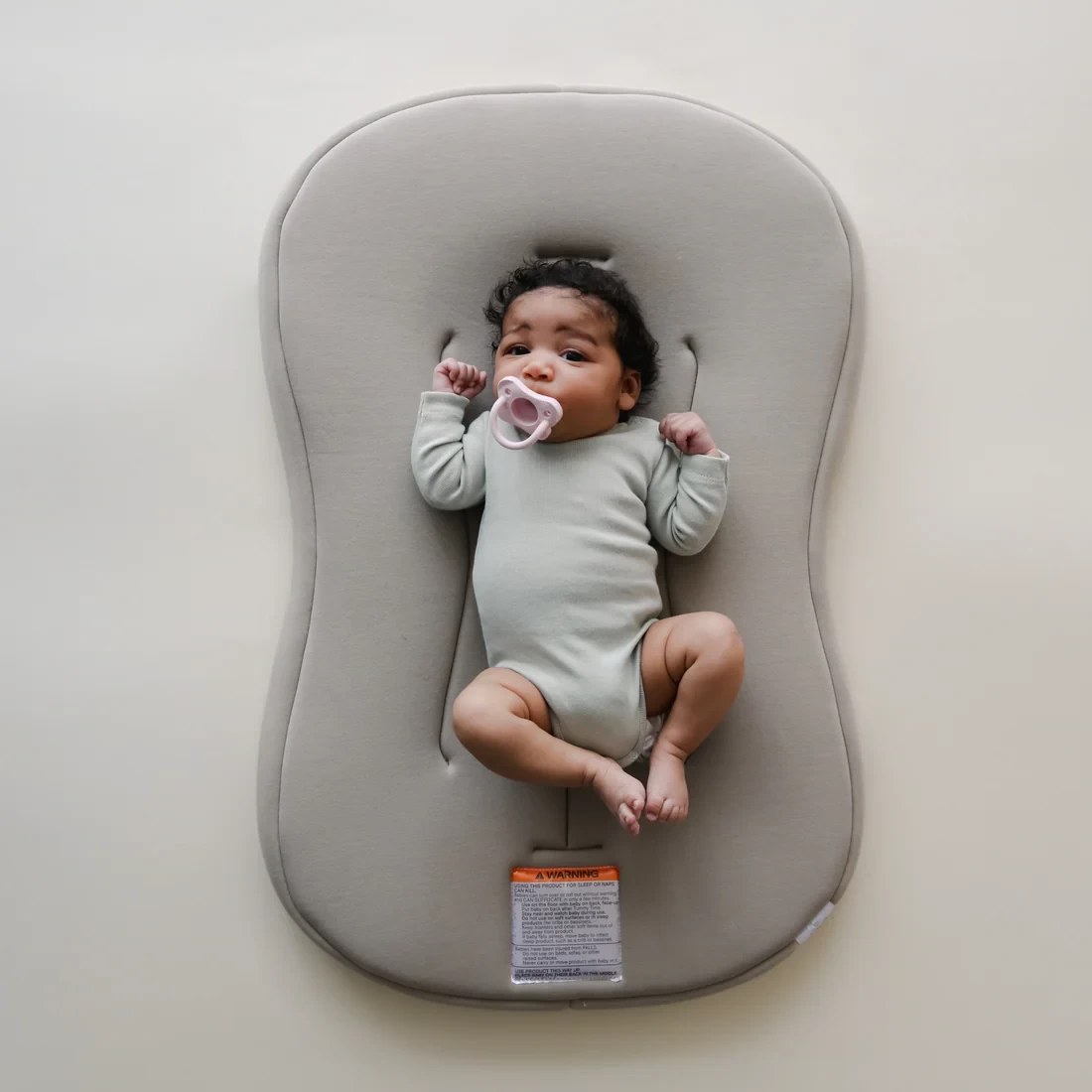 The SnuggleMe baby lounger with a baby lying safely on it