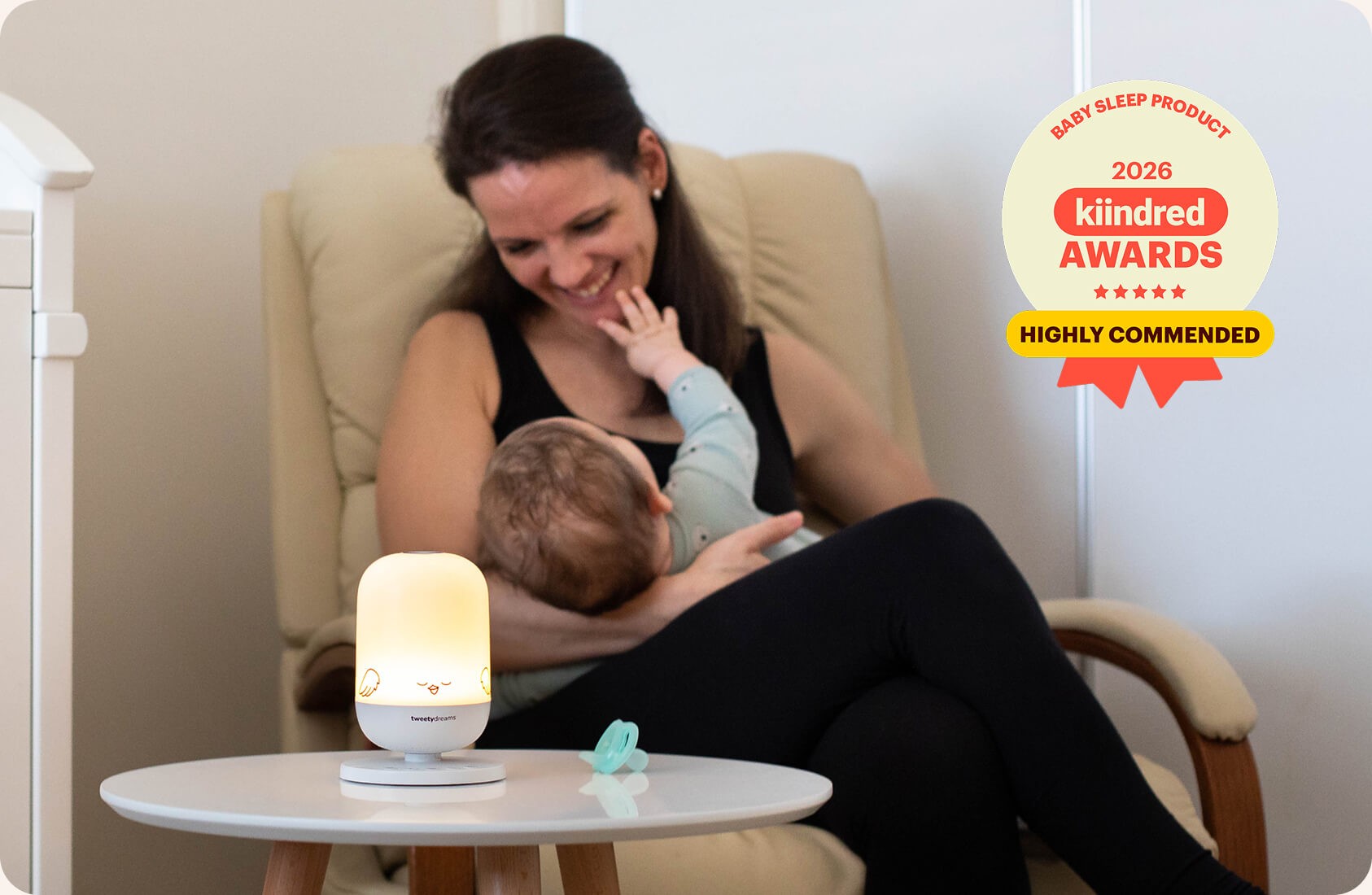 A mother nursing her baby next to a white noise machine