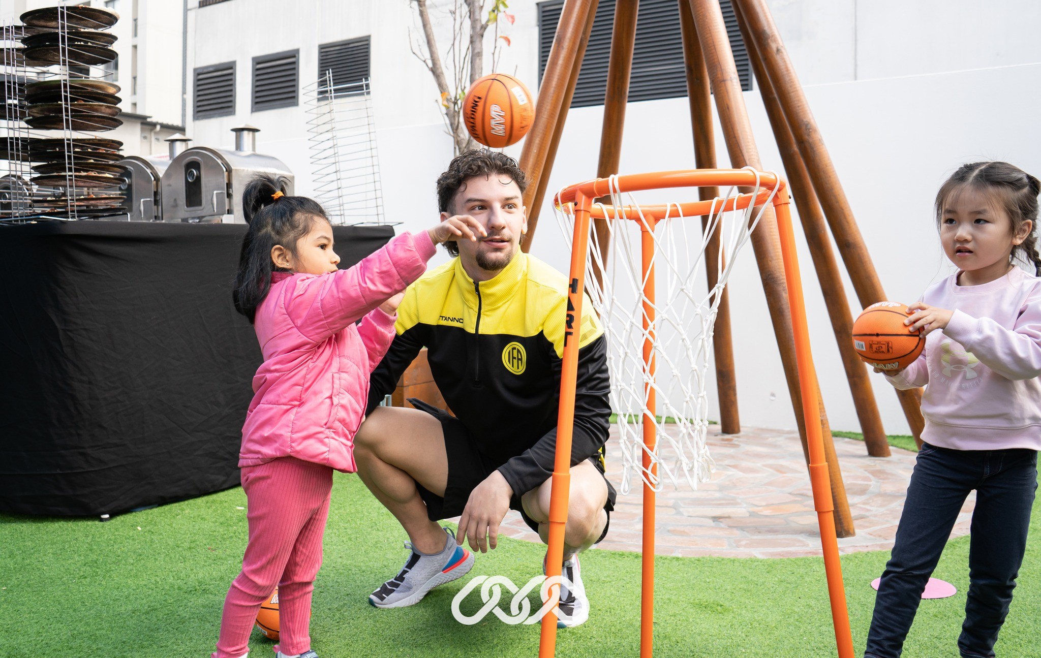 Toddler girl playing basketball with teacher support at the best childcare and daycare centre.