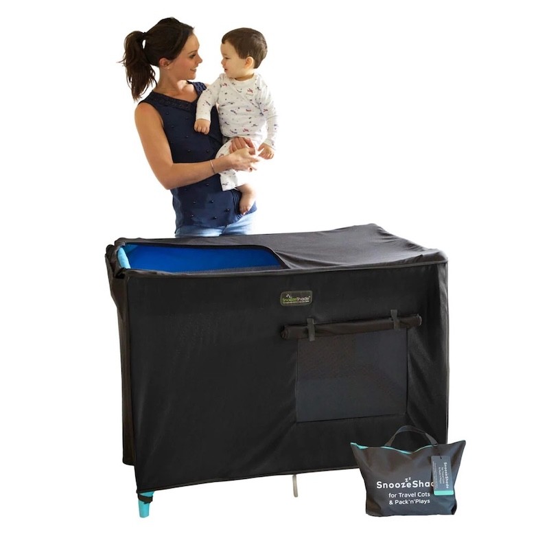 A mum holding her toddler while using the snoozeshade blockout cover