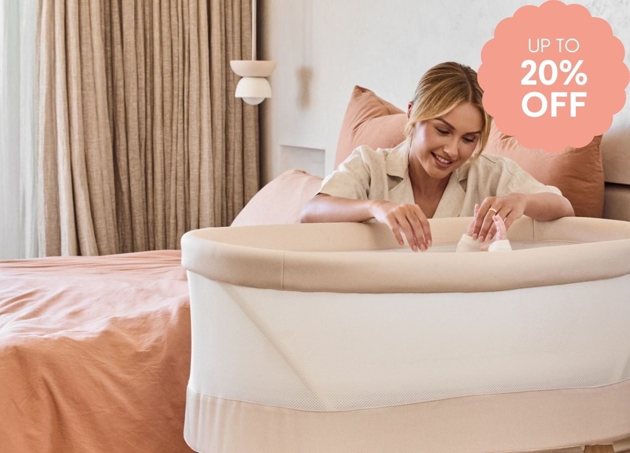 A mum tending to her baby in a bassinet