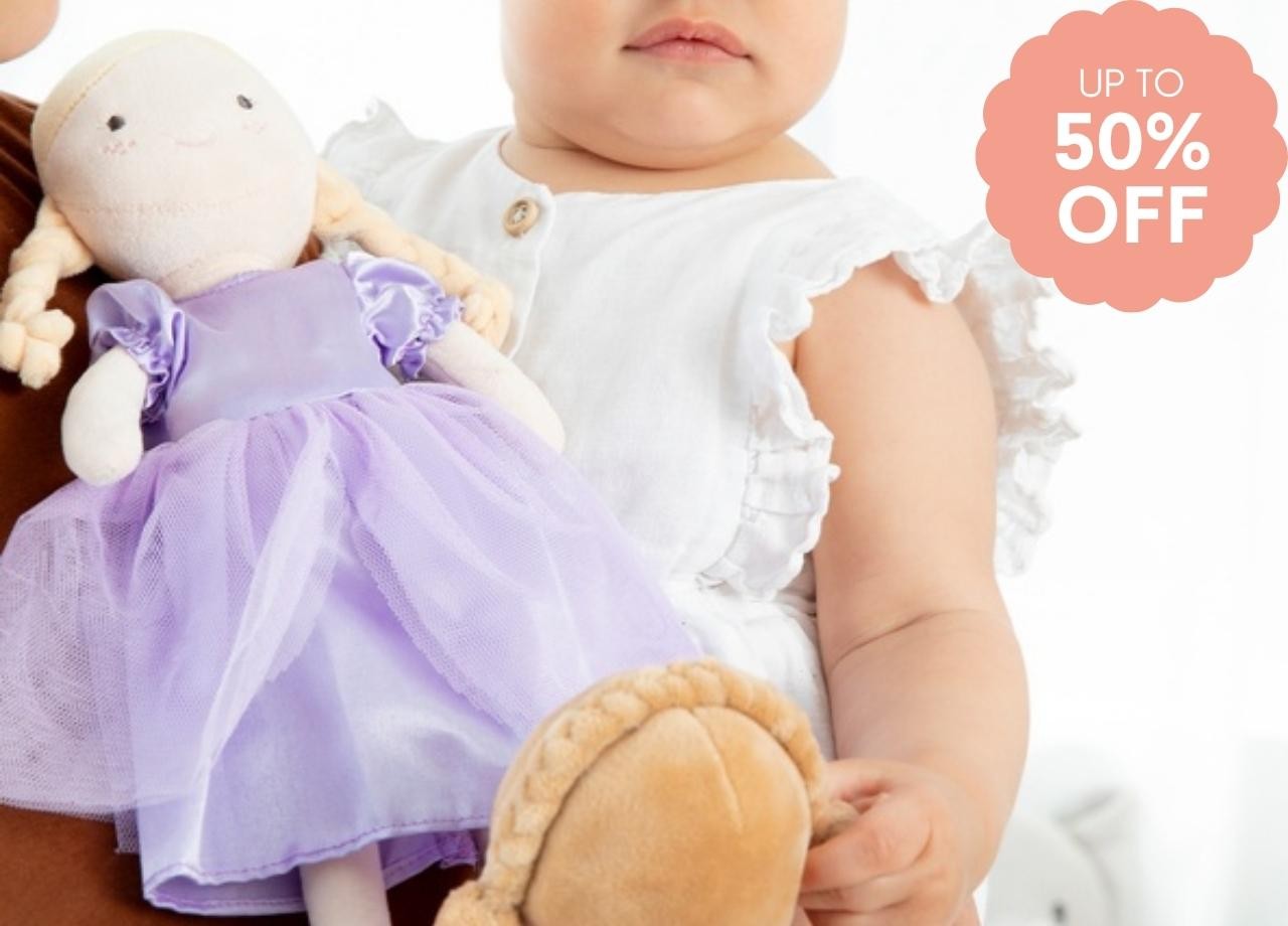 A baby holding two dolls
