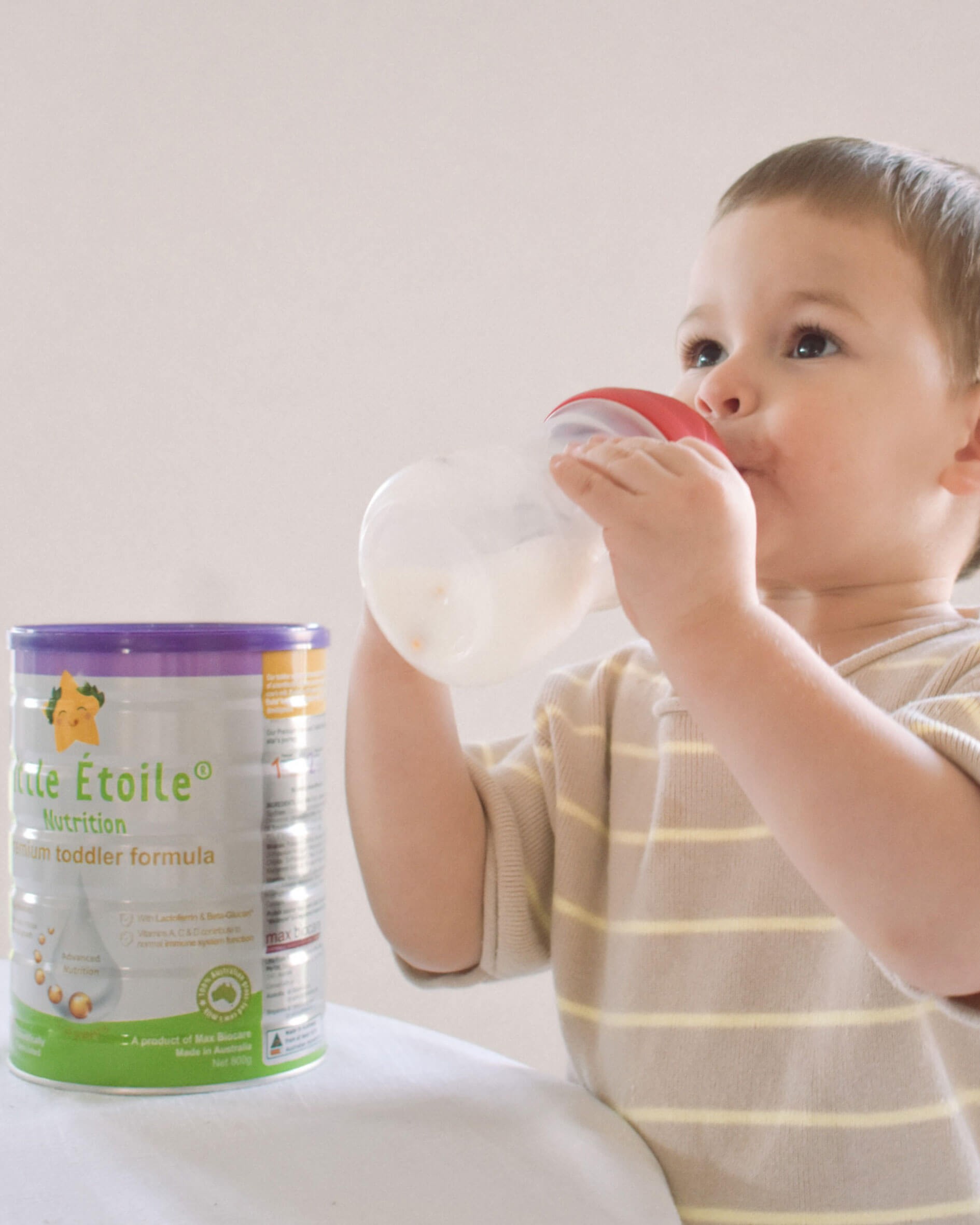 Toddler beside can of Little Étoile Nutrition Premium Toddler Formula while feeding from bottle – nourishing toddler feeding time