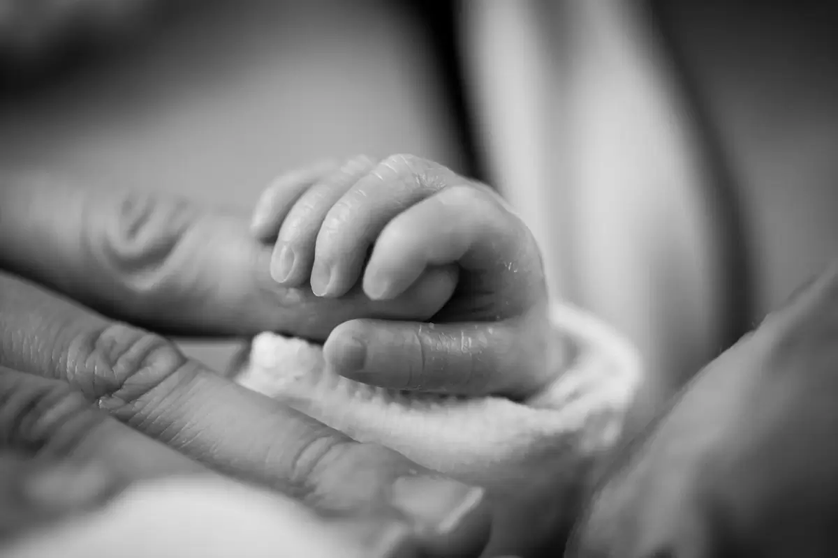 Mum holding her newborn’s hand after completing all stages of labour – a powerful post-birth moment