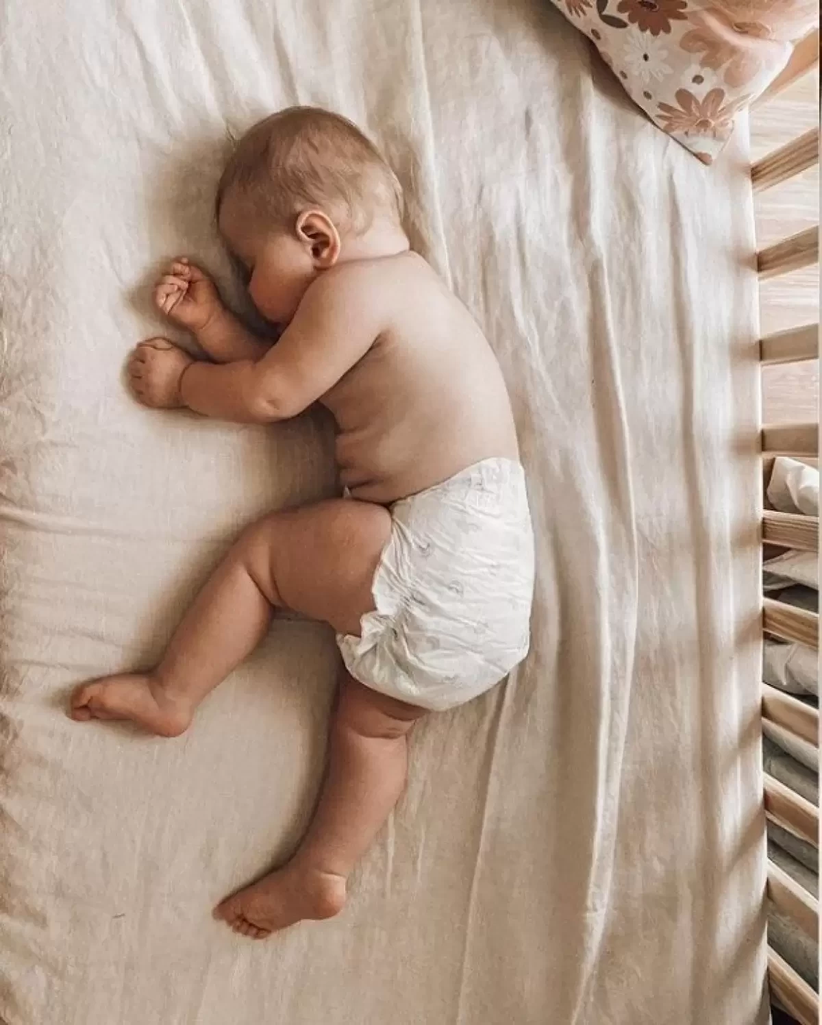 a baby in a nappy lying in a cot