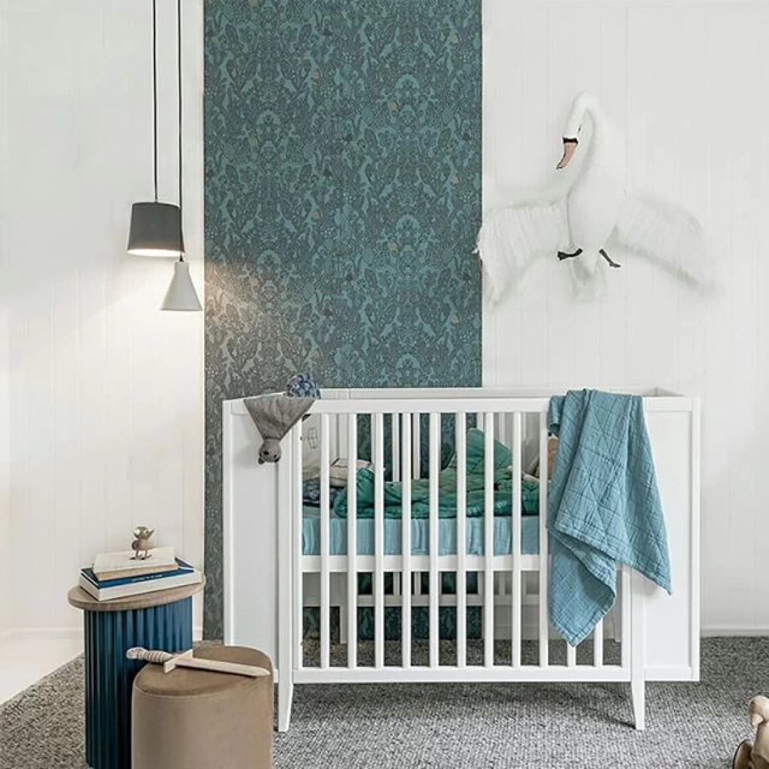 Nursery design with a white crib and blue-green blanket, reflecting the best baby boy nursery room decor ideas.