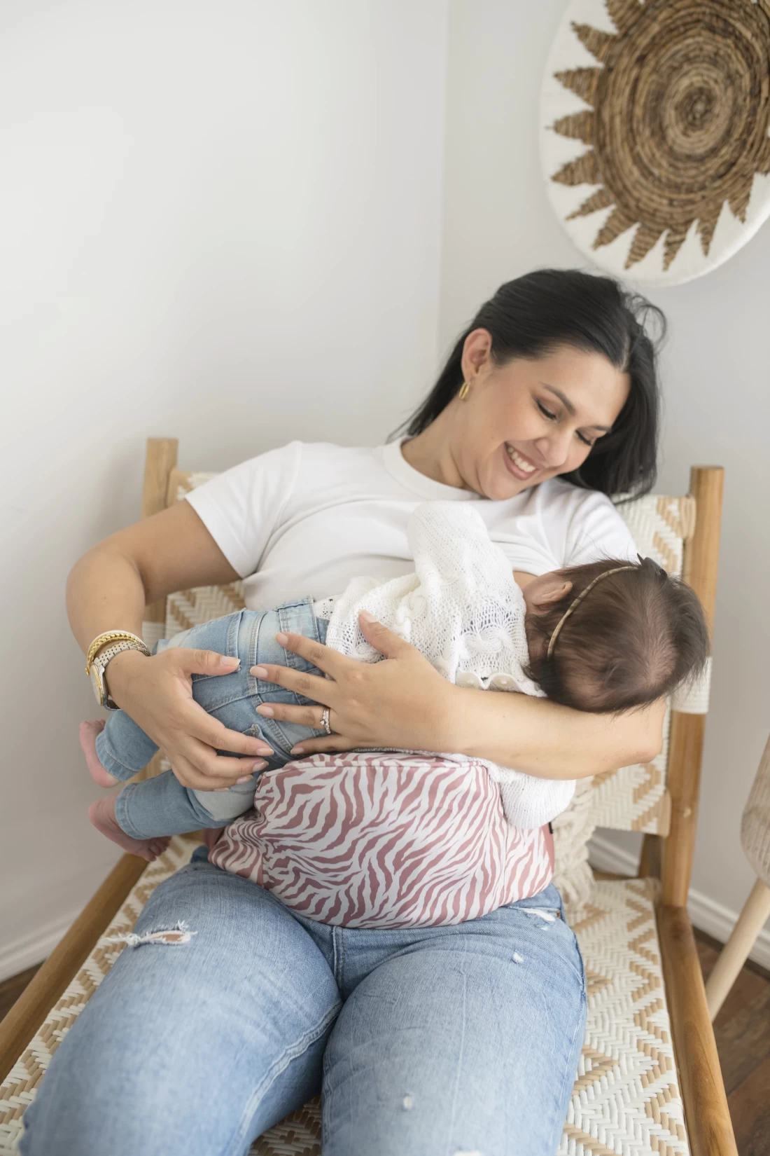 Mother sitting on a chair soothing her baby to sleep using the Hackerlily HipSurfer, the best baby carrier and bum bag.