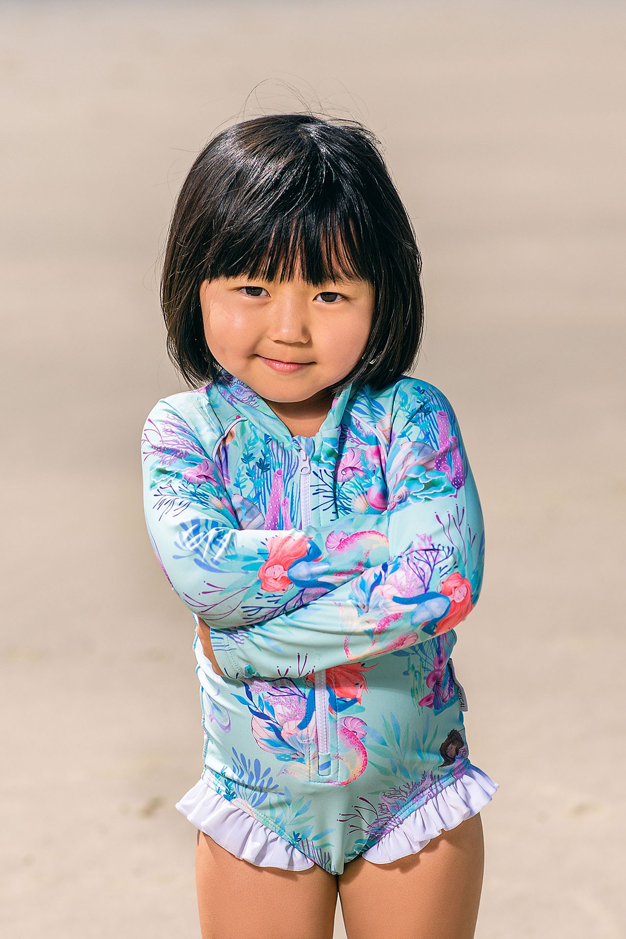 Australian toddler enjoying the beach in a sun-safe long-sleeve romper from the best swimwear brand in Australia.
