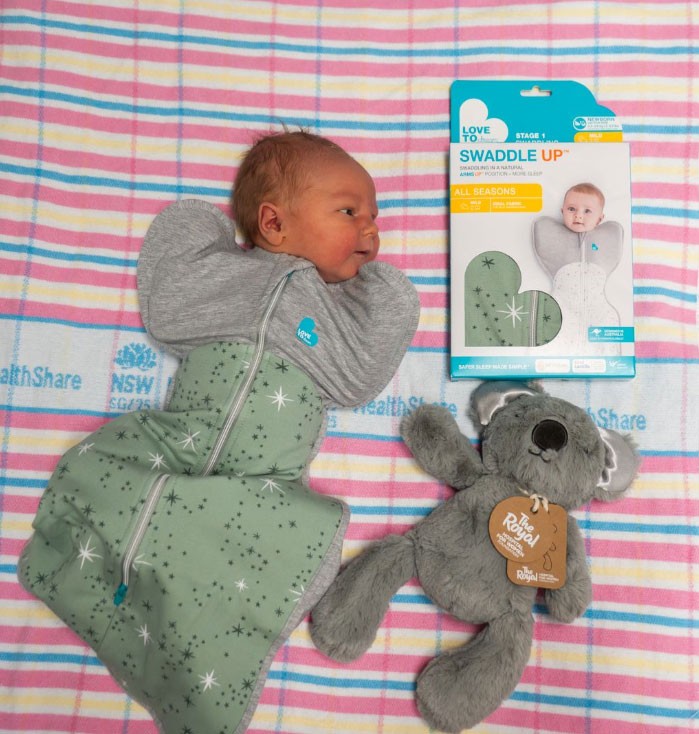 Love to Dream sleeping bag on a newborn baby with branded packaging and soft toy nearby.